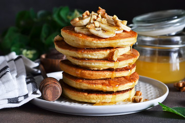 Homemade, hot pancakes with banana, honey and nuts on the kitchen table.