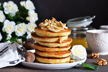 Homemade, hot pancakes with banana, honey and nuts on the kitchen table.