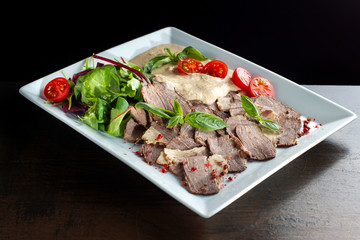 Meat cut with horseradish on a white plate.
