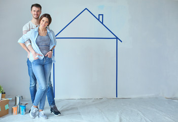 Couple standing in front of painted home on wall. Young couple