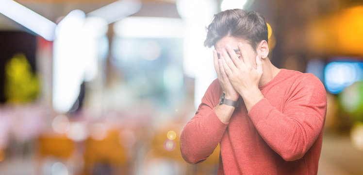 Young handsome man over isolated background with sad expression covering face with hands while crying. Depression concept.
