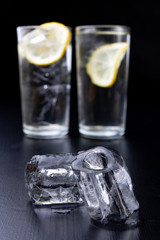 Cold drink in a glass on the kitchen table. Lemon and ice with water the best way to cool off on a summer day.