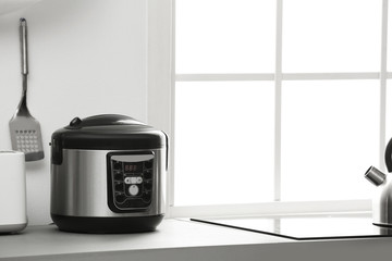 Modern electric multi cooker on kitchen countertop. Space for text