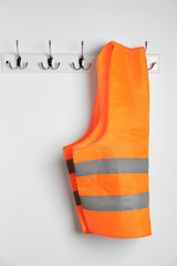 Reflective vest hanging on white wall. Safety equipment