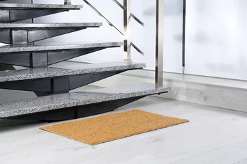 Abwaschbare Fototapete Treppen Neue Fußmatte in der Nähe von Steintreppen im Innenbereich