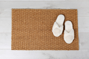 Fototapeta na wymiar Door mat and slippers on floor, top view. Space for text