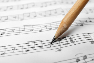 Sheet with music notes and pencil as background, closeup - obrazy, fototapety, plakaty