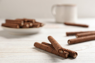 Delicious chocolate wafer rolls on white wooden table. Sweet food