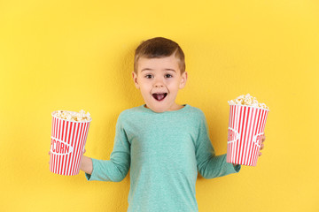 Cute little boy with popcorn on color background