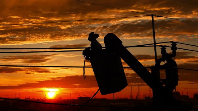 Silhouette of an electrician climbing a newly installed utility pole with sunset time lapse
