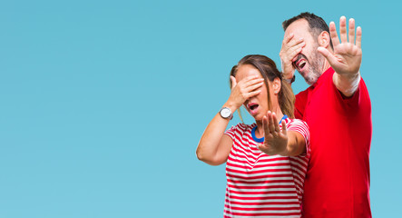 Middle age hispanic couple in love over isolated background covering eyes with hands and doing stop gesture with sad and fear expression. Embarrassed and negative concept.