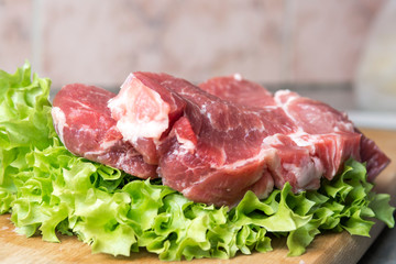 Pork-neck meat steaks on lettuce on background of radishes, tomato, red chili peppers, yellow chili peppers, green paprika, yellow paprika, red paprika, black pepper. Horizontal. Red onions, shallots