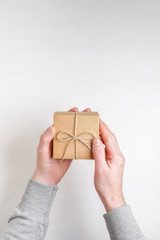 man's hands holds a gift in a box on a white background