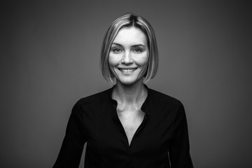 Black and white portrait of a beautiful smiling woman on a dark background