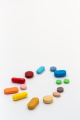 Circle of colored pills on white background. Legal drugs from the pharmaceutical industry.