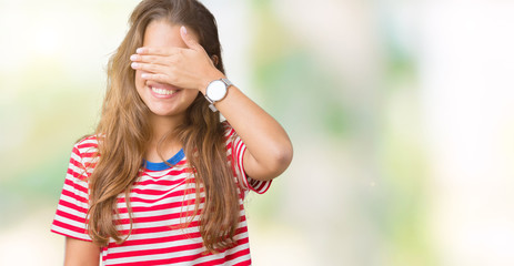 Young beautiful brunette woman wearing stripes t-shirt over isolated background smiling and laughing with hand on face covering eyes for surprise. Blind concept.