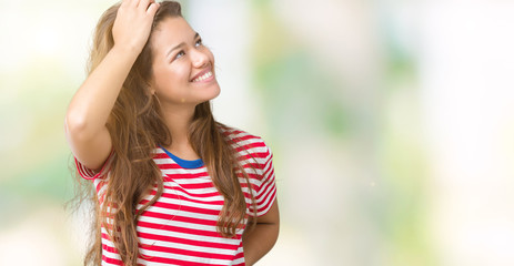 Young beautiful brunette woman wearing stripes t-shirt over isolated background Smiling confident touching hair with hand up gesture, posing attractive