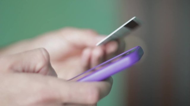 Close up man hands buying goods on smartphone with bank card.