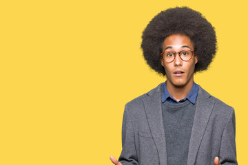 Young african american business man with afro hair wearing glasses afraid and shocked with surprise expression, fear and excited face.