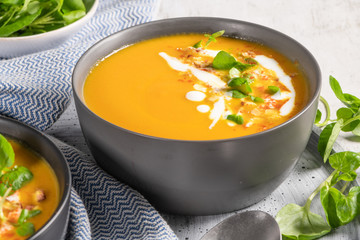 Pumpkin soup in bowl garnished with cream, hazelnut and watercress. Top view. Comfort food. Cream of pumpkin squash soup