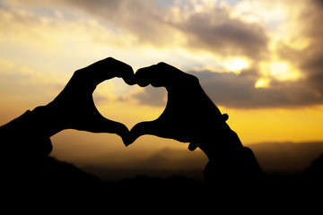 Heart shape from two hand with sunrise background.