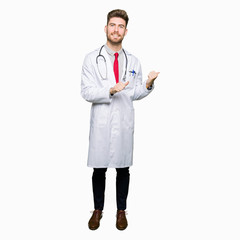 Young handsome doctor man wearing medical coat Pointing to the back behind with hand and thumbs up, smiling confident