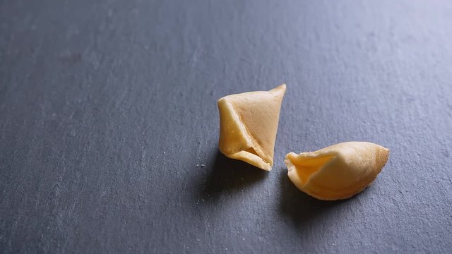 Close-up dolly shot of broken cookie with prediction on gray table background.
