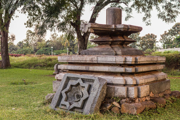 Fototapeta na wymiar Halebidu, Karnataka, India - November 2, 2013: Hoysaleswara Temple of Shiva. Large old Shivalingam on display on pedestal in temple museum garden.