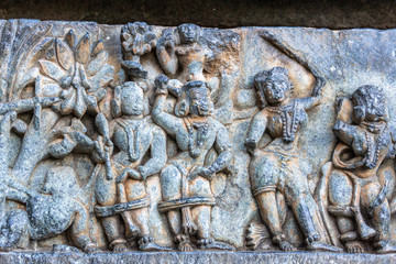 Halebidu, Karnataka, India - November 2, 2013: Hoysaleswara Temple of Shiva. Closeup of group of dancing girls statues on side of the temple structure in bluish stone and some brown background.