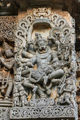 Fototapeta na wymiar Halebidu, Karnataka, India - November 2, 2013: Hoysaleswara Temple of Shiva. Closeup of statue on side of main sanctuary, where Narasiṃha, Vishnu avatar, kills Hiraṇyakasipu, statue in bluish gray sto