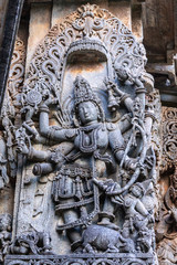 Halebidu, Karnataka, India - November 2, 2013: Hoysaleswara Temple of Shiva. Closeup of statue on side of main sanctuary, where Vishnu sets a foot on bull in bluish gray stone.