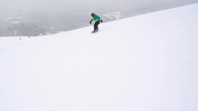 Extreme snowboarder riding fresh powder snow down the steep mountain slope