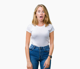 Beautiful young woman wearing casual white t-shirt over isolated background afraid and shocked with...