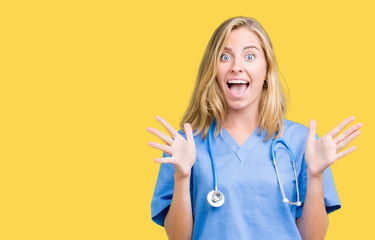 Beautiful young doctor woman wearing medical uniform over isolated background celebrating crazy and...