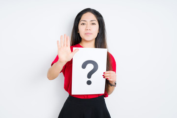 Young brunette woman holding paper with question mark over isolated background with open hand doing stop sign with serious and confident expression, defense gesture