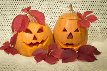two amusing pumpkins in a crimson autumn leaf
