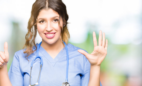 Young adult doctor woman wearing medical uniform showing and pointing up with fingers number six while smiling confident and happy.