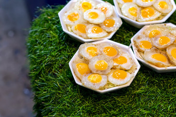 Fried quail eggs in foam boxes on artificial grass.