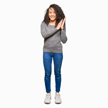 Young beautiful woman with curly hair wearing grey sweater Clapping and applauding happy and joyful, smiling proud hands together