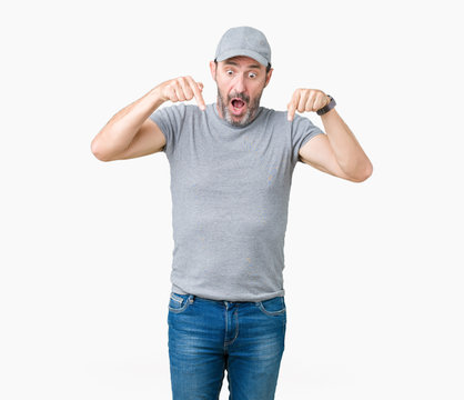 Handsome middle age hoary senior man wearing sport cap over isolated background Pointing down with fingers showing advertisement, surprised face and open mouth