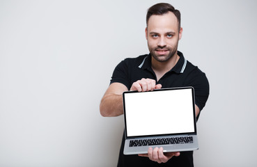 Young confident man holding laptop with mockup over white background.