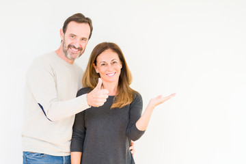 Beautiful middle age couple in love over isolated background Showing palm hand and doing ok gesture with thumbs up, smiling happy and cheerful