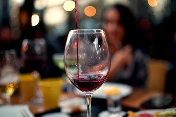 red wine  filled wine glass in front of blurred bokeh young gouple