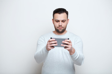Serious man using smartphone over white background.