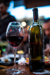 wine bottle with wine glass of red wine front of blurred young couple