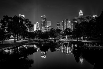 Fototapeta na wymiar The Uptown skyline and a lake at Marshall Park at night, in Charlotte, North Carolina.