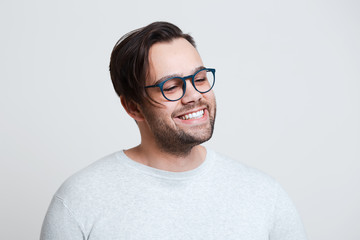 Obraz premium Portrait of young happy man wearing blue glasses over white background.