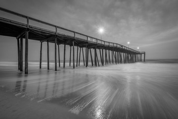 Waves in the Atlantic Ocean and the fishing pier at twilight, in Ocean City, Maryland.