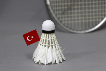 Mini Turkey flag stick on the white shuttlecock on the grey background and out focus badminton racket.