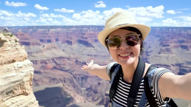 happy college girl student exchange studying in america sightseeing on summer vacation in Grand Canyon National Park arizona usa. young asian woman waving hand talking video phone call sending kiss